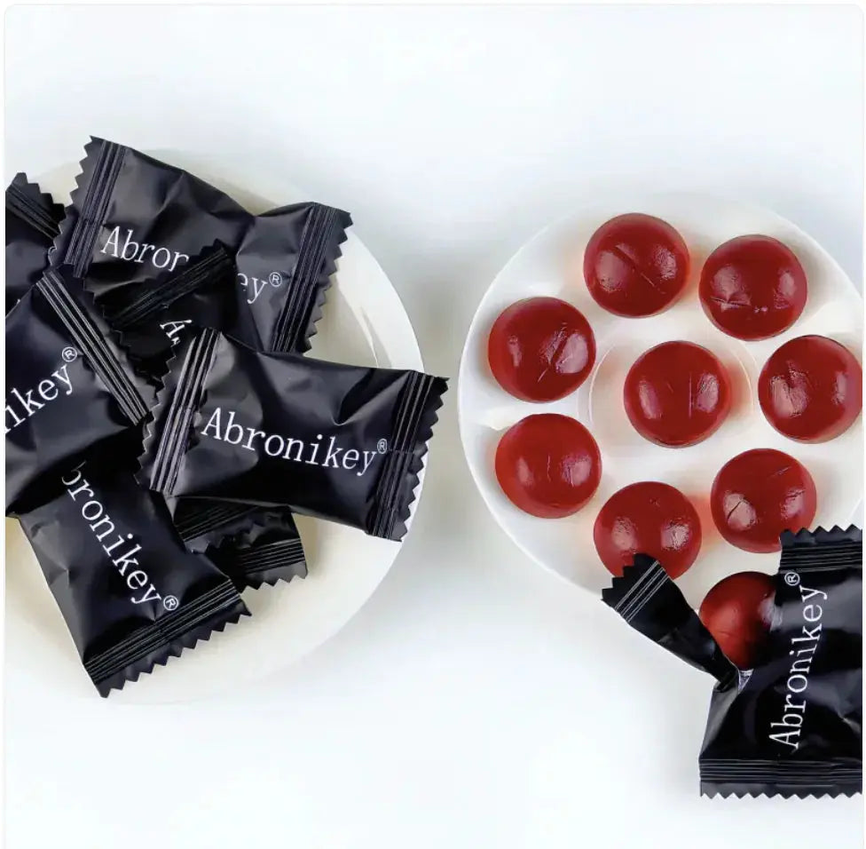 Allebuy shilajit gummies in black Abronikey wrappers and unwrapped red gummy supplements on white plates