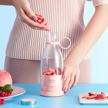 Ninja blast portable blender in pink with fresh strawberries being added for juice making