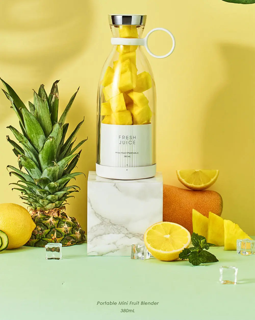 Ninja blast portable blender with fresh pineapple chunks inside on marble block surrounded by fruits